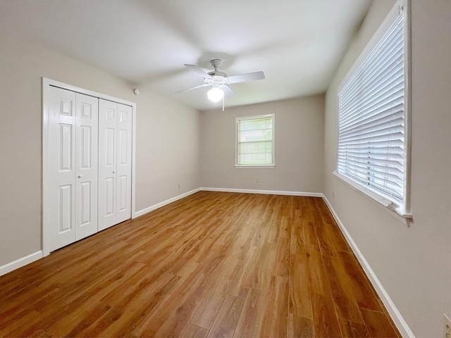 unfurnished bedroom featuring light wood-style floors, baseboards, ceiling fan, and a closet