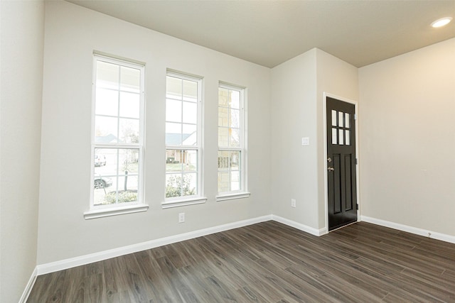 spare room with baseboards, dark wood finished floors, and a wealth of natural light