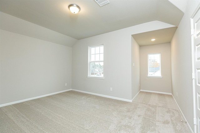unfurnished room with vaulted ceiling, baseboards, light colored carpet, and visible vents