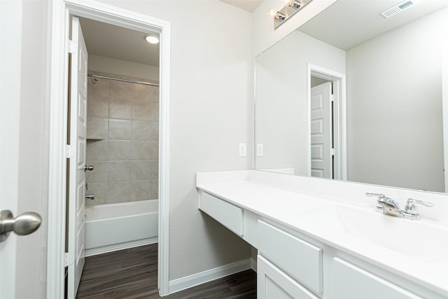 full bathroom featuring visible vents, vanity, wood finished floors, baseboards, and shower / washtub combination