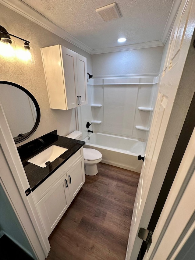 bathroom with vanity, toilet, a textured ceiling, wood finished floors, and ornamental molding