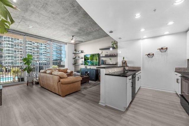 kitchen featuring ceiling fan, a peninsula, light wood-type flooring, expansive windows, and dishwashing machine