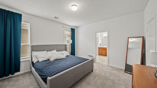 6630 Elks Trce, Richmond, TX 77406 - bedroom featuring visible vents, a textured ceiling, ensuite bathroom, and light colored carpet