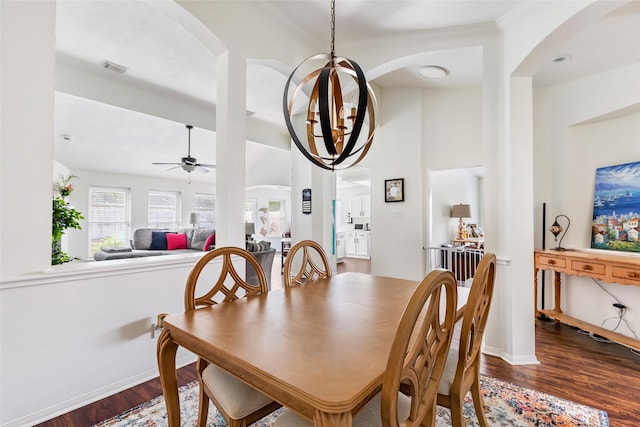 dining area featuring arched walkways, wood finished floors, a ceiling fan, and baseboards