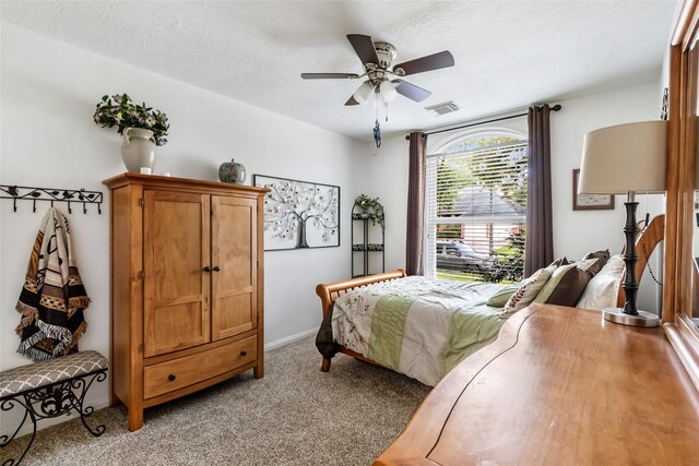 bedroom featuring light carpet, a textured ceiling, and ceiling fan