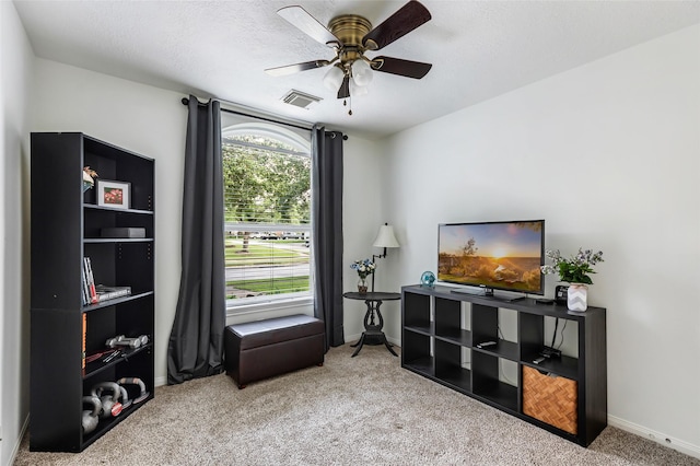living area featuring carpet flooring, baseboards, and a ceiling fan