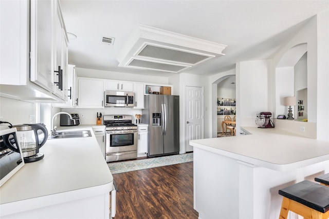 kitchen with stainless steel appliances, a peninsula, a sink, light countertops, and white cabinetry
