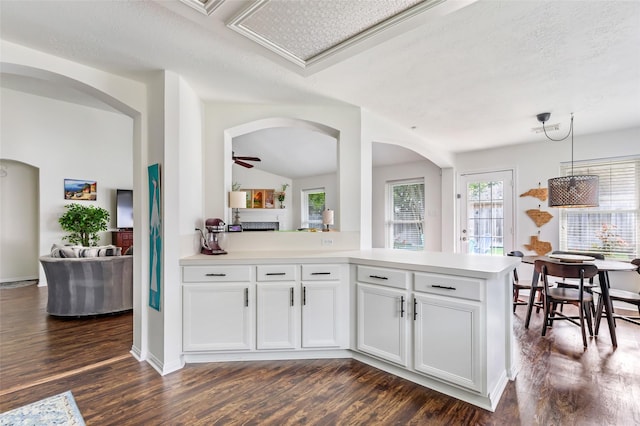 kitchen with dark wood finished floors, a peninsula, white cabinets, light countertops, and a textured ceiling