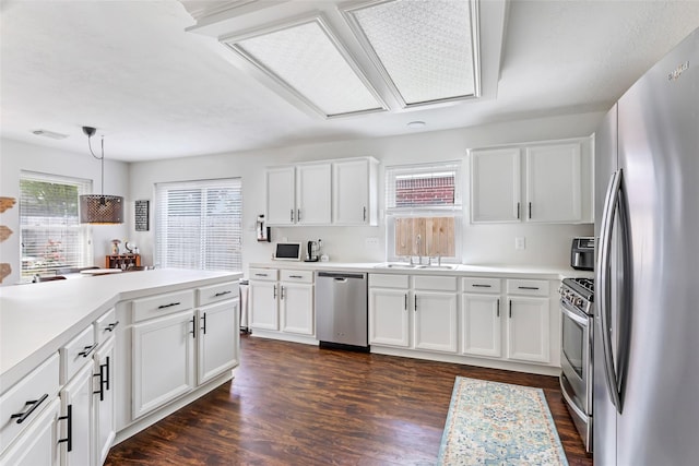 kitchen featuring stainless steel appliances, a sink, white cabinetry, light countertops, and dark wood finished floors