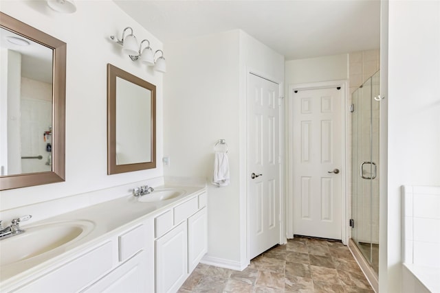 bathroom with a stall shower, double vanity, and baseboards