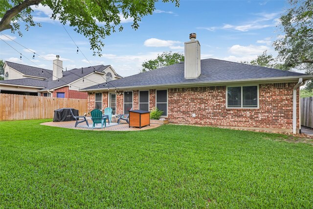 rear view of house featuring brick siding, a patio, a shingled roof, and a chimney