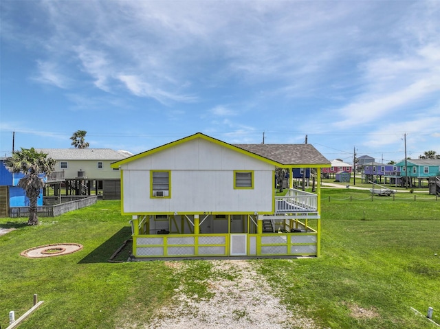 rear view of house with fence, a shingled roof, a yard, and a fire pit