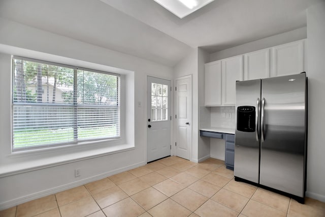 67 N Winterport Cir, The Woodlands, TX 77382 - kitchen with stainless steel fridge, light tile patterned floors, light countertops, white cabinets, and vaulted ceiling