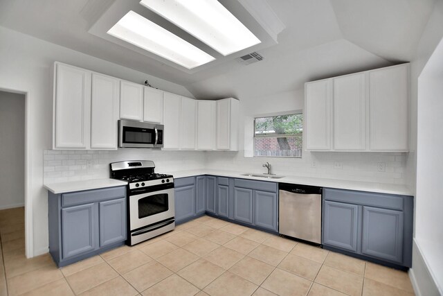 67 N Winterport Cir, The Woodlands, TX 77382 - kitchen with appliances with stainless steel finishes, a sink, vaulted ceiling, light countertops, and decorative backsplash