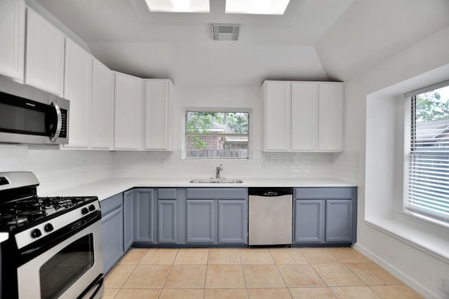 67 N Winterport Cir, The Woodlands, TX 77382 - kitchen featuring appliances with stainless steel finishes, a sink, healthy amount of natural light, lofted ceiling, and gray cabinetry