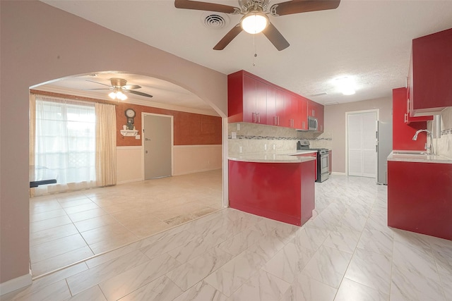 7022 Triola Ln, Houston, TX 77074 - kitchen with light countertops, arched walkways, ceiling fan, and stainless steel appliances