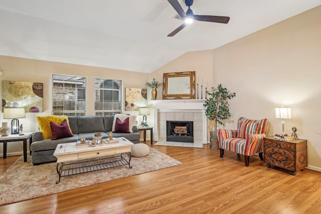 living room featuring ceiling fan, a fireplace, vaulted ceiling, and wood finished floors