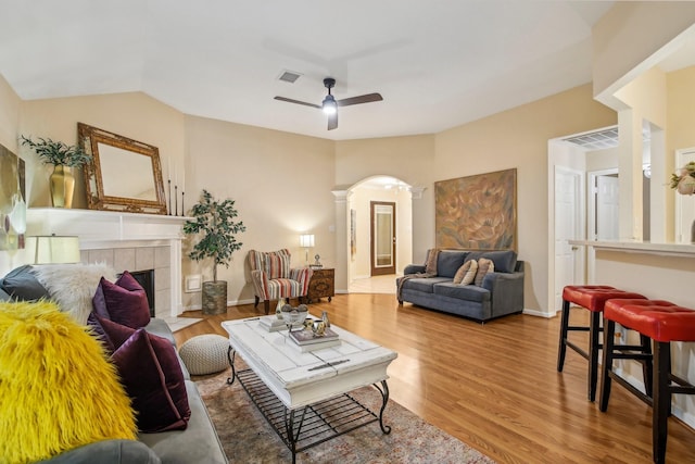 living area with a ceiling fan, decorative columns, visible vents, arched walkways, and wood finished floors