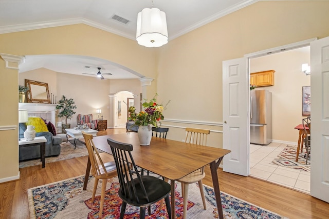 dining area featuring ceiling fan, arched walkways, decorative columns, vaulted ceiling, and visible vents