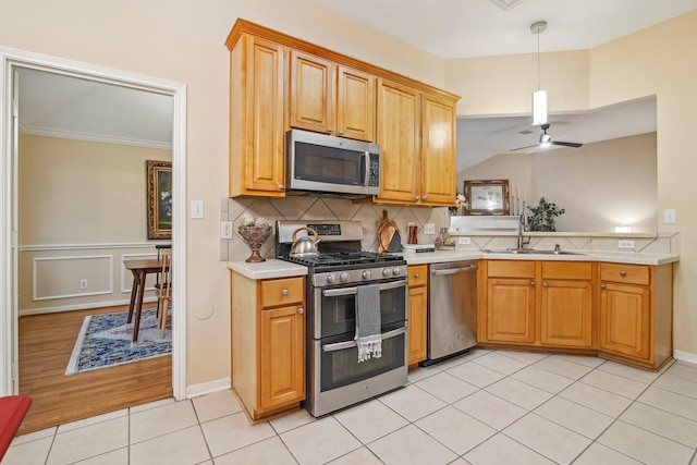 kitchen featuring a ceiling fan, appliances with stainless steel finishes, a sink, light countertops, and light tile patterned flooring