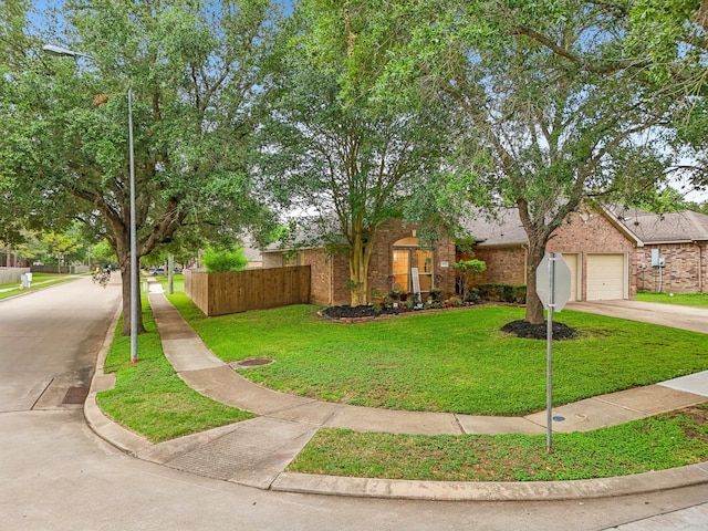view of front facade featuring fence, driveway, a front lawn, and brick siding