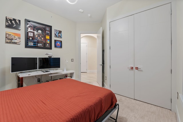 bedroom with arched walkways, a closet, and light colored carpet