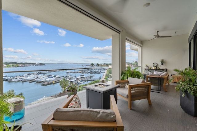 balcony with a water view, an outdoor living space with a fire pit, and ceiling fan