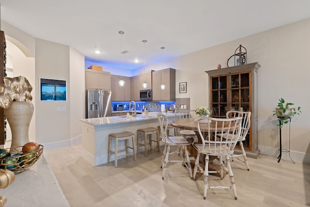 kitchen featuring light stone countertops, appliances with stainless steel finishes, a breakfast bar area, a peninsula, and baseboards