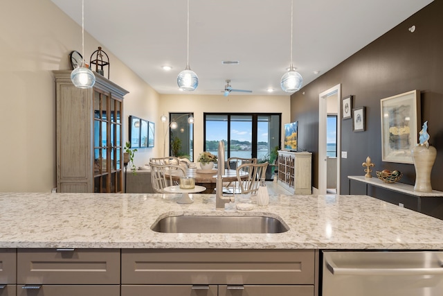 kitchen with a sink, gray cabinetry, and light stone countertops