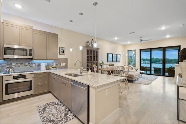 kitchen with appliances with stainless steel finishes, a sink, gray cabinets, a peninsula, and tasteful backsplash