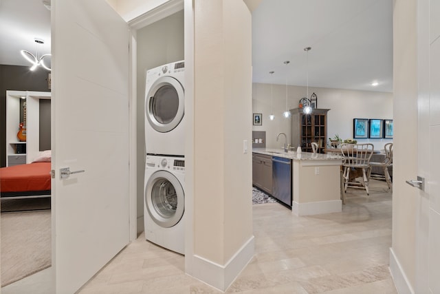 washroom with baseboards, laundry area, stacked washing maching and dryer, and a sink