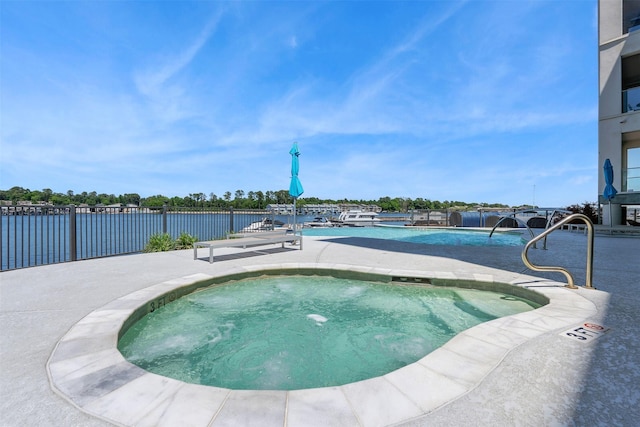 community pool featuring a patio, a water view, and fence