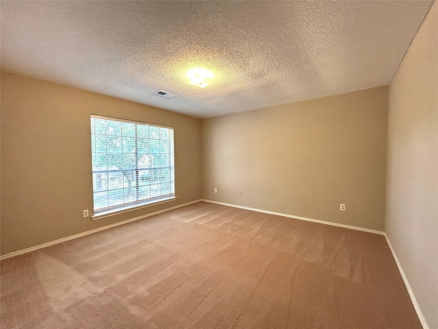 carpeted spare room featuring baseboards, a textured ceiling, and visible vents
