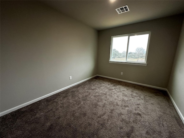 empty room featuring visible vents, baseboards, and dark colored carpet