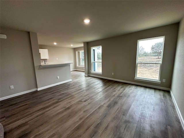 unfurnished living room with recessed lighting, baseboards, and dark wood finished floors