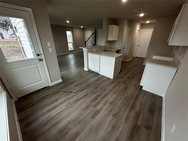 kitchen with white cabinets, a sink, light countertops, a peninsula, and visible vents