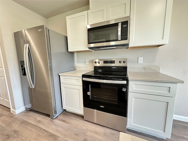 kitchen featuring white cabinets, stainless steel appliances, light countertops, and light wood-style floors