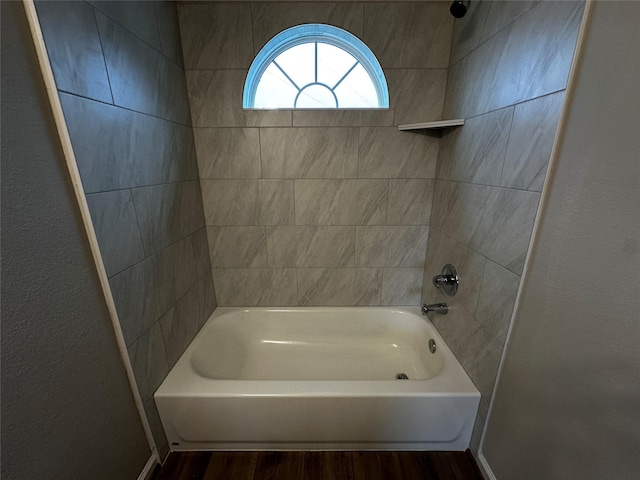bathroom with baseboards, wood finished floors, and shower / washtub combination