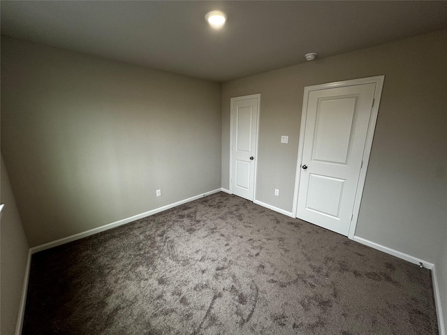 unfurnished bedroom featuring baseboards and dark colored carpet