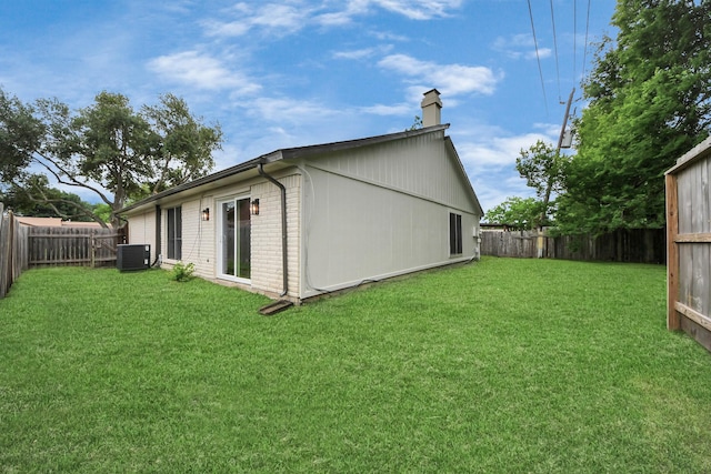 rear view of property with central AC unit, a chimney, and brick siding