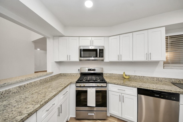 kitchen with appliances with stainless steel finishes, white cabinets, and light stone counters