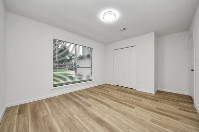unfurnished bedroom with light wood-style floors, baseboards, and a closet