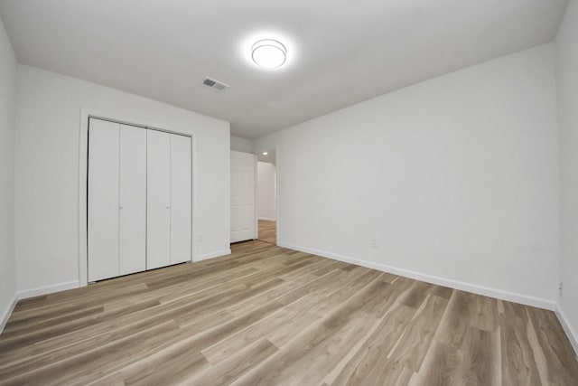 unfurnished bedroom with baseboards, light wood-style flooring, and a closet