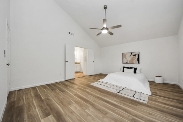 unfurnished bedroom featuring high vaulted ceiling, light wood-style flooring, baseboards, ensuite bath, and ceiling fan