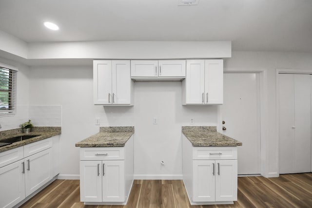 kitchen featuring stone countertops, dark wood-style flooring, white cabinets, a sink, and recessed lighting