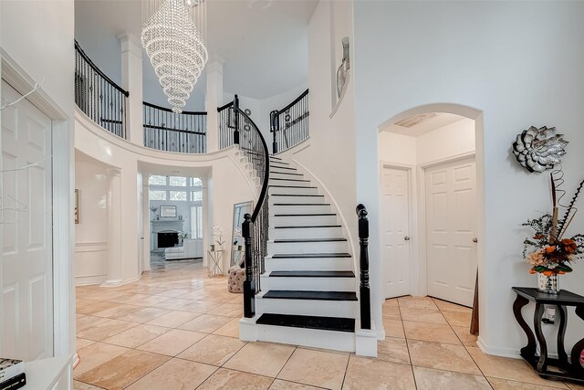 2703 Marble Brook Ln, Pearland, TX 77584 - foyer entrance featuring stairs, a high ceiling, arched walkways, light tile patterned floors, and a notable chandelier