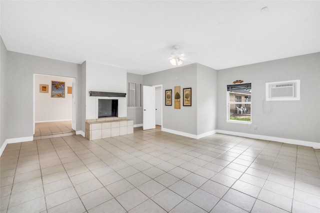 6803 Lakemont Dr, Houston, TX 77050 - unfurnished living room with ceiling fan, a tiled fireplace, baseboards, a wall unit AC, and light tile patterned floors
