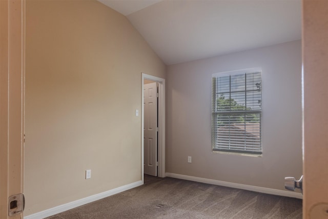 spare room featuring carpet floors, lofted ceiling, and baseboards