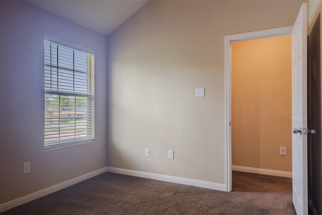 unfurnished room with dark carpet, baseboards, and lofted ceiling