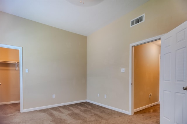 unfurnished bedroom featuring carpet, a spacious closet, baseboards, and a closet